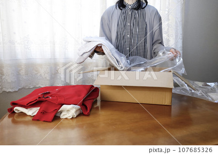 洋服をネットショッピングで購入 早速開封する女性 洋服をネットショッピングで購入 早速開封する女性 107685326