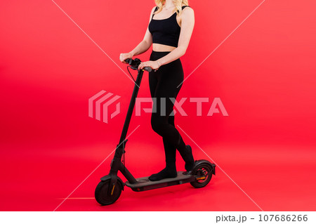 Blonde woman on red and white background sit and stand with electro scooter and resting 107686266