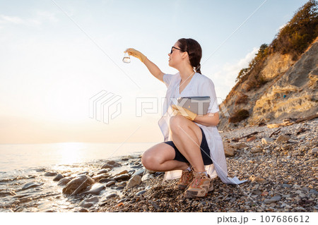 Young Caucasian woman ecologist in rubber gloves examines test flask of water. Copy space. Concept of ecology and environment pollution Young Caucasian woman ecologist in rubber gloves examines test flask of water. Copy space. Concept of ecology and environment pollution 107686612
