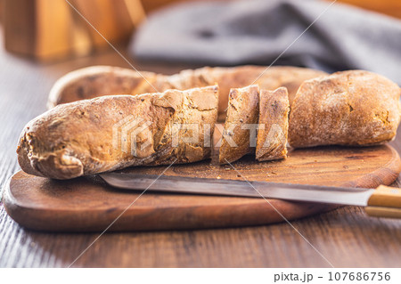 Wholegrain rustical baguette on wooden table. 107686756
