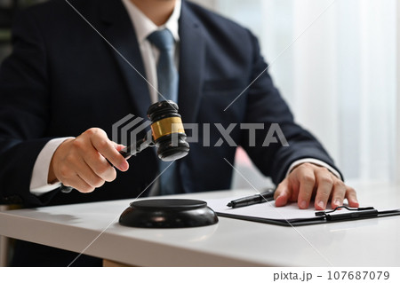 Unrecognizable judge holding gavel to bang on sounding block. Lawyer, justice and law, attorney concept Unrecognizable judge holding gavel to bang on sounding block. Lawyer, justice and law, attorney concept 107687079