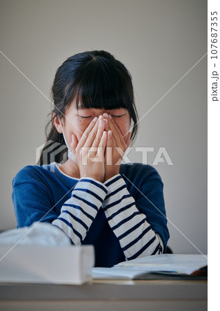 手で鼻を押さえる小学生の女の子 107687355