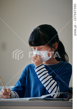 風邪をひいて咳をする小学生の女の子 107687360