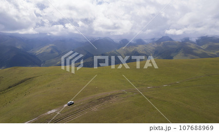 A white SUV rides in the mountains through fields 107688969