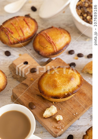 Pasticciotto leccese pastry filled with egg custard cream on a wooden board and coffee close up 107689186