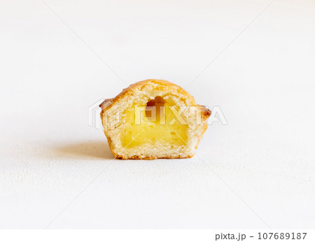 Half of Pasticciotto leccese pastry filled with egg custard cream on a white table, close up 107689187