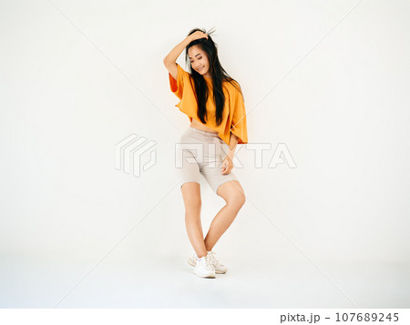 Full length portrait of smiling asian female posing on white background 107689245