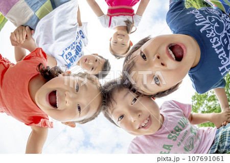 公園の草地で遊ぶ小学生たち 107691061