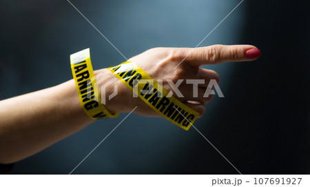Hand with warning tape shows signs Hand with warning tape shows signs 107691927