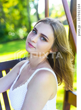 Belarus woman in white dress sitting on wooden swings Belarus woman in white dress sitting on wooden swings 107692164