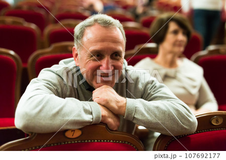 Mature man in theater watching a performance Mature man in theater watching a performance 107692177