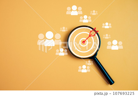 Customer group icons in a magnifying glass placed on a yellow background represent the selection of business goals, target customers. Marketing plans and strategies, customer-centric strategies. 107693225