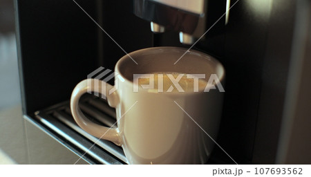 Coffee machine pours coffee into mug. Woman takes the finished drink. Drinking coffee in the morning. Close up. Coffee machine pours coffee into mug. Woman takes the finished drink. Drinking coffee in the morning. Close up. 107693562