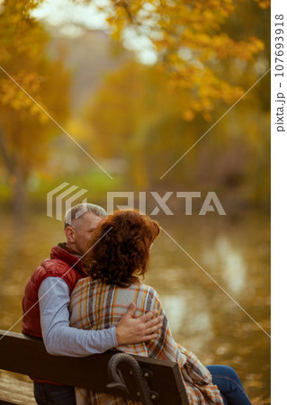 Seen from behind romantic family in park sitting on bench 107693918