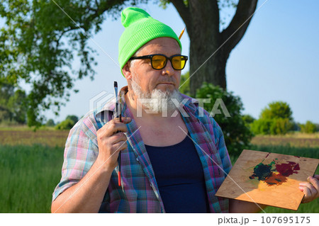 Arttist going to create, holds painting tools outdoors at dawn Arttist going to create, holds painting tools outdoors at dawn 107695175