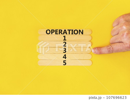 Time to operation 3 symbol. Concept word Operation 1 2 3 4 5 on wooden sticks. Businessman hand. Beautiful yellow table yellow background. Business planning and time to operation 3 concept. Copy space 107696623