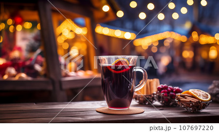 Traditional mulled wine in a glass mug on an empty tabletop at Christmas street fair with bright lights and festive atmosphere 107697220