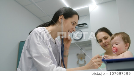 Baby sits on changing table in hospital room 107697399