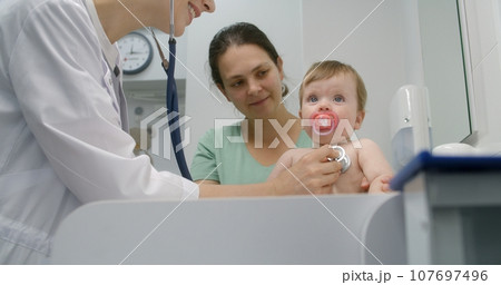 Baby sits on changing table in hospital room 107697496