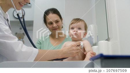 Baby sits on changing table in hospital room Baby sits on changing table in hospital room 107697509