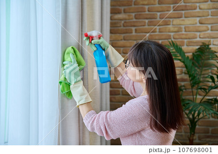 Close-up of woman in gloves cleaning curtains 107698001