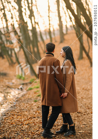 Young couple in love walking in the park on a autumn day. Enjoying time together. Young couple in love walking in the park on a autumn day. Enjoying time together. 107698011