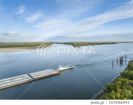 towboat with barges on the Mississippi River at confluence with the Missouri River below Alton, IL towboat with barges on the Mississippi River at confluence with the Missouri River below Alton, IL 107698945