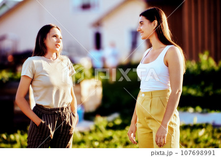 Two young neighbors chat on rural street on summer day. 107698991