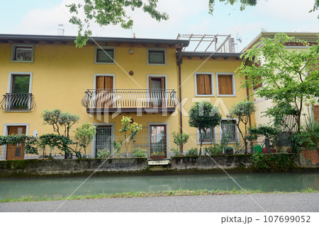 Beautiful apartment building by the river in the Alps of Italy Beautiful apartment building by the river in the Alps of Italy 107699052