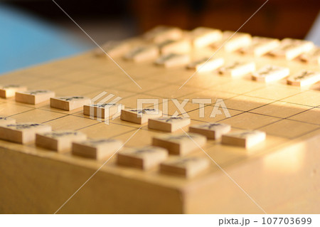 明るい光の中の将棋盤の上に並んだ将棋の駒 107703699