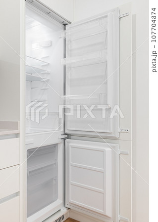 Photo of an open, empty and white refrigerator in a modern kitchen 107704874