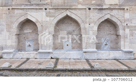 Stone wall of 16th century historic Atik Valide Mosque with row of ablution fountains, Uskudar, Istanbul, Turkey Stone wall of 16th century historic Atik Valide Mosque with row of ablution fountains, Uskudar, Istanbul, Turkey 107706012