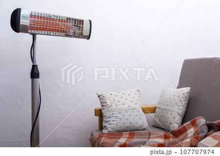 Electric infrared heater warming up living room with sofa at background Electric infrared heater warming up living room with sofa at background 107707974