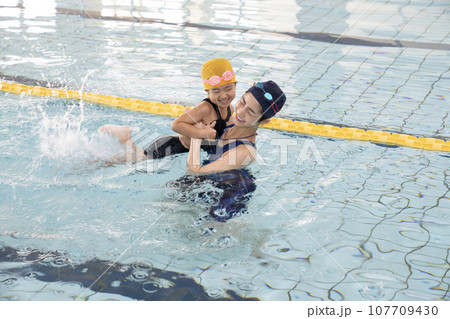 プールで女の子の手を引く水泳コーチ 107709430