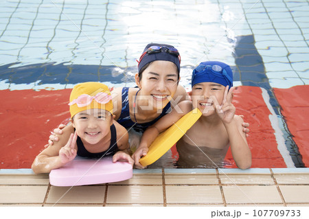 室内プールでビート板を持つ兄弟と水泳教室の先生 室内プールでビート板を持つ兄弟と水泳教室の先生 107709733