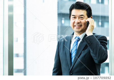 オフィスでスマホで電話をするミドルの経営者 107709892