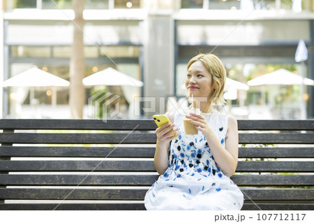 ベンチに座ってアイスコーヒーを飲む女性 ベンチに座ってアイスコーヒーを飲む女性 107712117