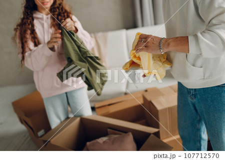Happy young family couple man and woman unpacking box after moving cardboard boxes to new home apartment. 107712570