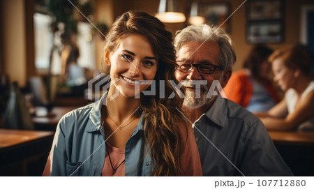 Portrait of two happy smiling owners of family restaurant. Senior mature man and young attractive woman running small business. Father and his adult daughter successful entrepreneurs. 107712880