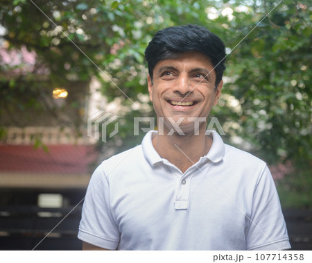 Smart Indian man in white standing outdoors Smart Indian man in white standing outdoors 107714358