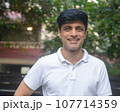 Smart Indian man in white standing outdoors 107714359