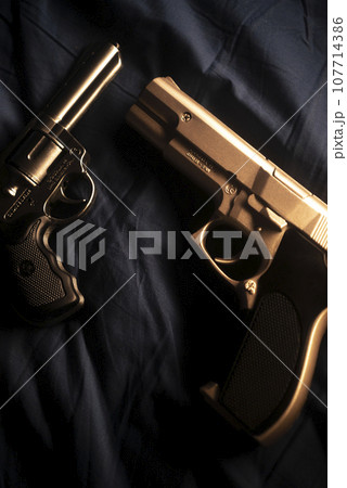 Pistol gun on bed sheet 107714386