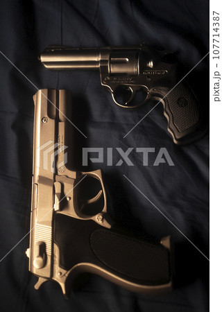 Pistol gun on bed sheet 107714387