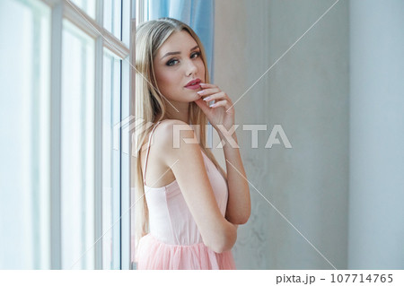 Young pretty woman standing at window and enjoying vacation Young pretty woman standing at window and enjoying vacation 107714765