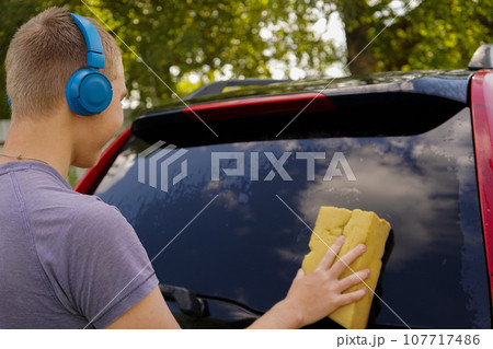 Teenager Boy Washing and Cleaning car in front of his House 107717486