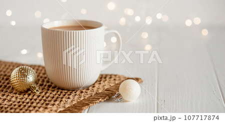 A white cup with hot coffee or tea on a white wooden table. A white cup with hot coffee or tea on a white wooden table. 107717874