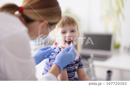 Doctor takes an analysis from little girl with cotton swab Doctor takes an analysis from little girl with cotton swab 107720163