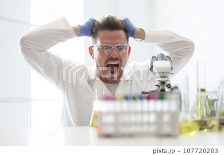 Research assistant looks enthusiastically at microscope closeup 107720203