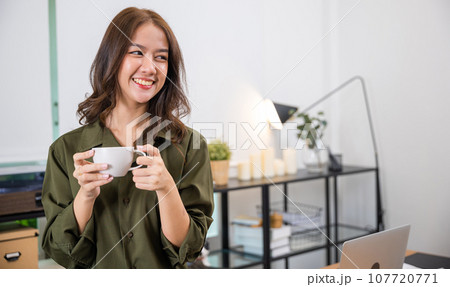 Portrait of Asian young woman holding hot coffee or tea cup in morning while posing, white porcelain mug mock up, Happy beautiful woman relaxing in summer after wakeup at home, lifestyle 107720771