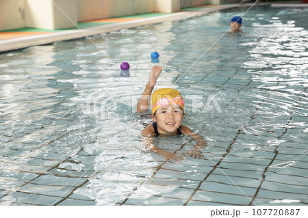 子供用プールで泳ぐ少女 107720887